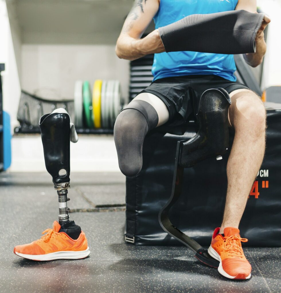 Disabled athlete assembling his leg prosthesis in the gym. Paralympic Sport Concept.